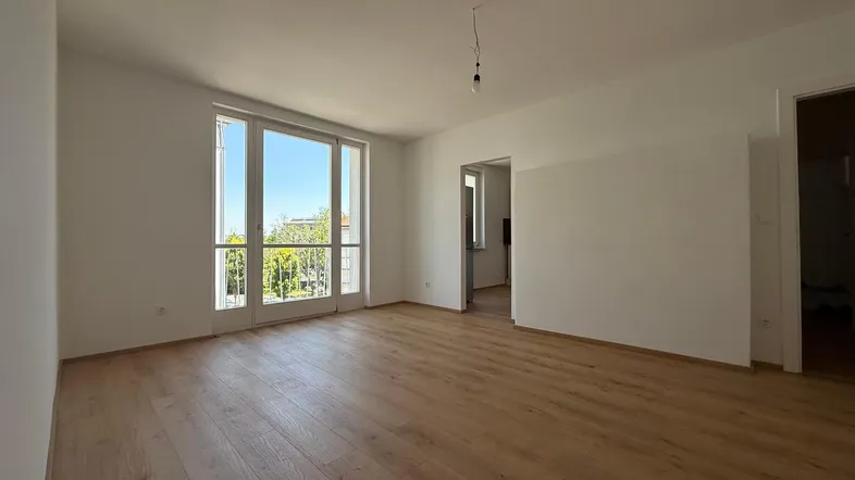 Helles Wohnzimmer mit neuem Laminatboden und Zugang zu einem französischen Balkon.