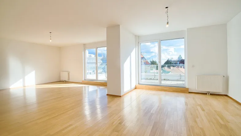 Helles Wohnzimmer mit großen Fenstern, Parkettboden und Heizkörpern, bietet viel natürliches Licht.