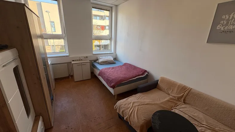 Helles Schlafzimmer mit Einzelbett, Sofa und Kleiderschrank, ideal für Studenten oder Gäste.