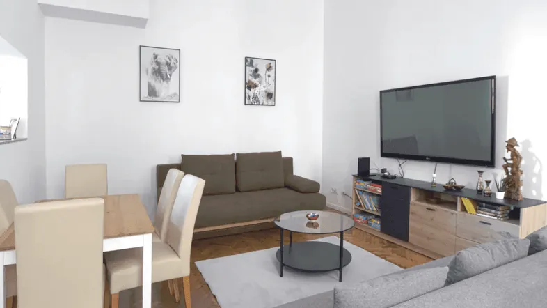 Helles Wohn- und Esszimmer mit Parkettboden, bequemen Sofas und einem Esstisch.