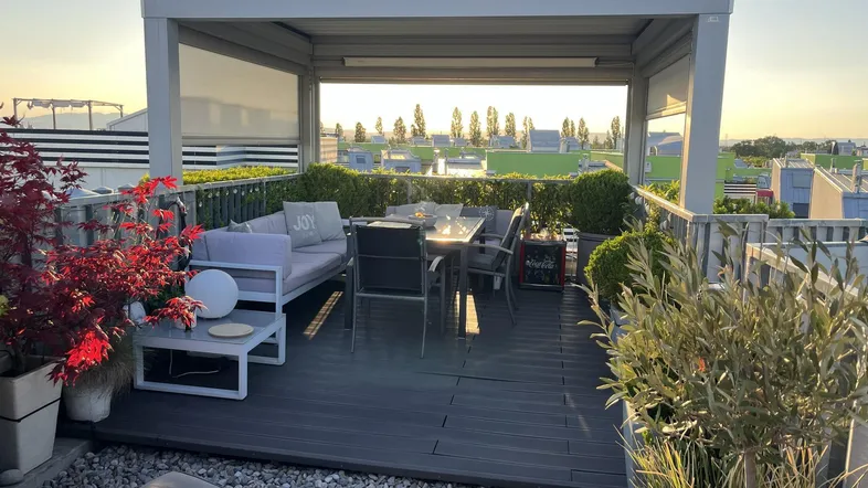 Geräumige Dachterrasse mit gemütlichen Loungemöbeln, Essbereich und Pergola, ideal für entspannte Abende.