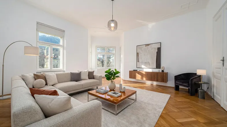 Helles Wohnzimmer mit modernem Sofa, Holzboden und Blick auf die Berge.