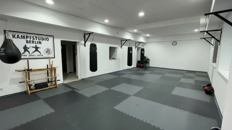Geräumiger Kampfsportraum mit Boxsäcken und schützendem Bodenbelag, ideal für Trainingseinheiten und Kurse.