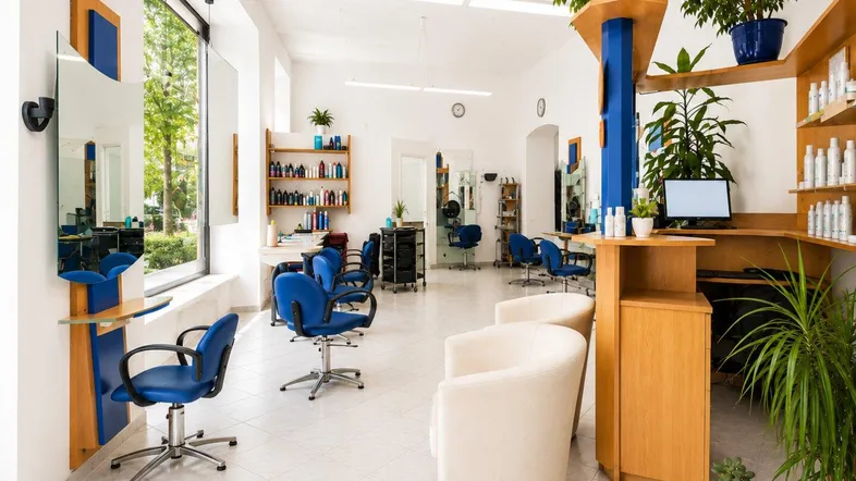 Heller und geräumiger Friseursalon mit blauen Stühlen, großen Fenstern und viel natürlichem Licht.
