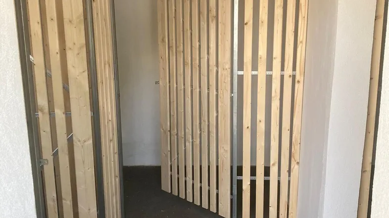 Kellerraum mit individuellen Holzabtrennungen für separate Lagerbereiche und Betonboden.