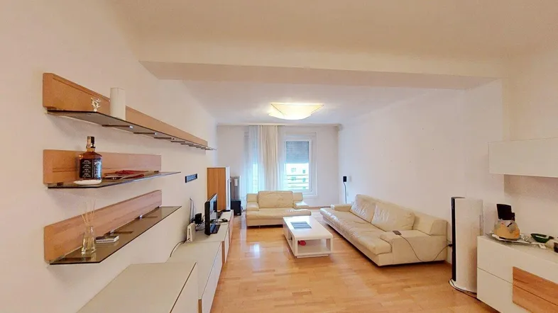 Helles Wohnzimmer mit beigen Sofas, Holzparkettboden und modernen Wandregalen.