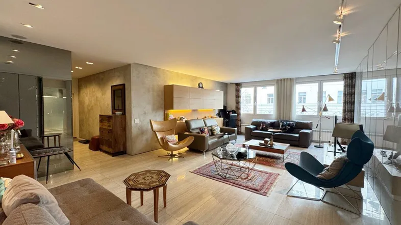Geräumiges Wohnzimmer mit modernen Möbeln, Fliesenboden und indirekter Beleuchtung.