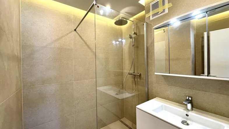 Modernes Badezimmer mit begehbarer Dusche, Einzelwaschbecken und hellen Fliesen an den Wänden.