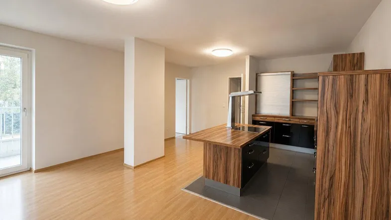 Heller offener Wohnbereich mit Holzboden und integrierter Küche, ideal für modernes Wohnen.