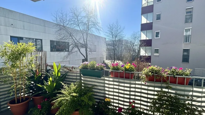 Sonniger Balkon mit vielen Pflanzen und Blumenkästen, bietet einen grünen Ausblick auf die Umgebung.