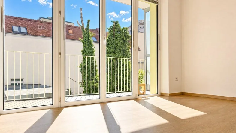 Heller Wohnraum mit großen Fenstern, die viel Tageslicht hereinlassen und Blick ins Grüne bieten.