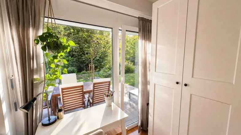 Heller Arbeitsbereich mit Schreibtisch, Pflanzen und Blick auf den grünen Garten.