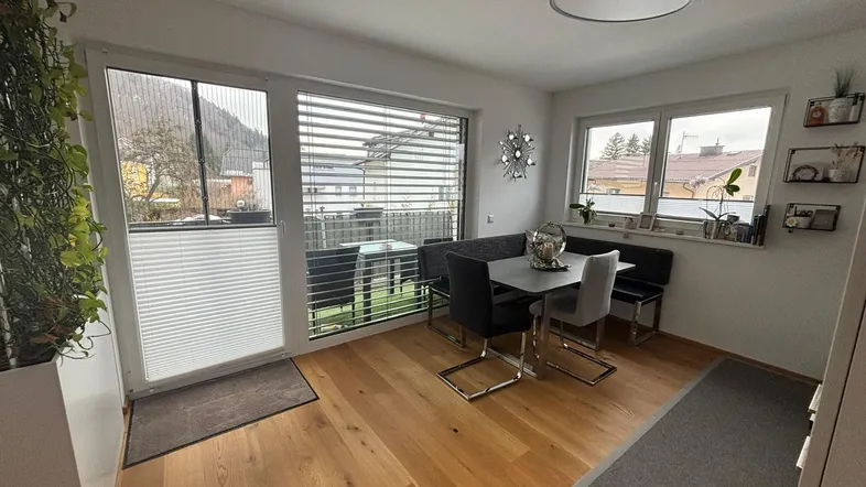 Heller Essbereich mit Holzboden, großem Fenster und Zugang zum Balkon, ideal für gemeinsame Mahlzeiten.