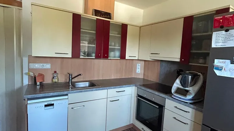 Moderne Küche mit beigen und weinroten Schränken, ausgestattet mit Geschirrspüler und Backofen.