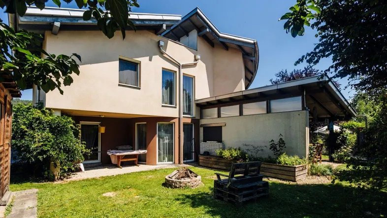 Rückseite des Hauses mit gepflegtem Garten, Rasenfläche und Feuerstelle für gemütliche Abende.