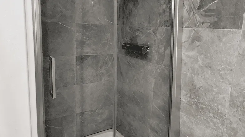Modernes Badezimmer mit grauen Marmorfliesen und einer geräumigen Duschkabine aus Glas.