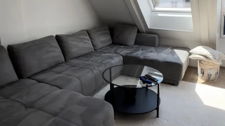 Gemütliches Wohnzimmer mit großem Ecksofa, modernem Couchtisch und viel Tageslicht durch das Dachfenster.