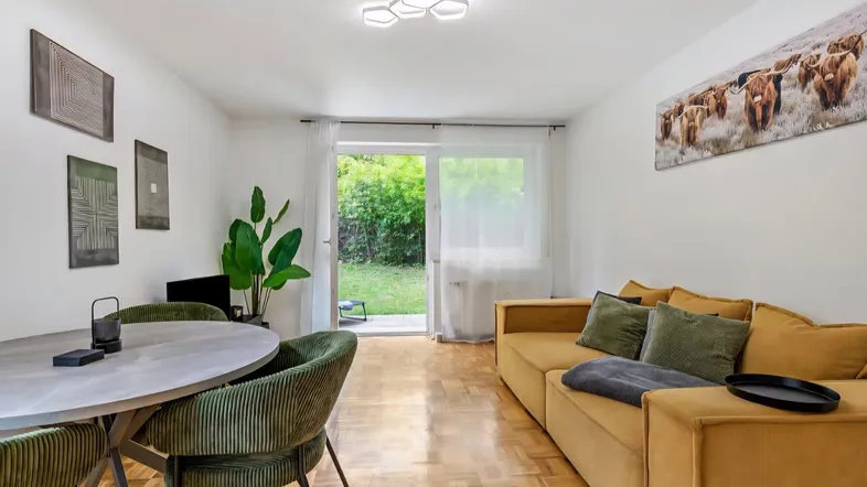 Heller Wohn- und Essbereich mit Parkettboden und direktem Zugang zum privaten Garten.