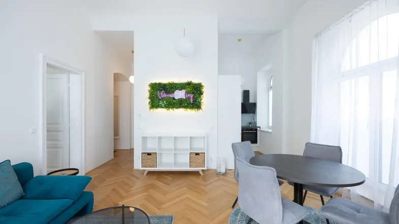 Helles Wohn- und Esszimmer mit Fischgrätparkett, moderner Einrichtung und dekorativer Wandbegrünung.