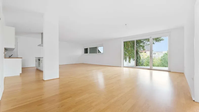 Heller, offener Wohnbereich mit Parkettboden und großen Schiebetüren, die Zugang zur Terrasse bieten.
