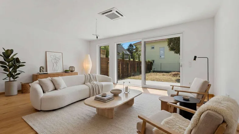 Helles Wohnzimmer mit modernem Mobiliar, Holzboden und direktem Zugang zum Garten.