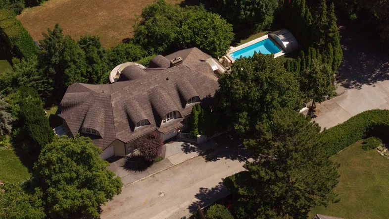 Luftaufnahme eines Anwesens mit großem Haus, weitläufigem Garten und Swimmingpool.
