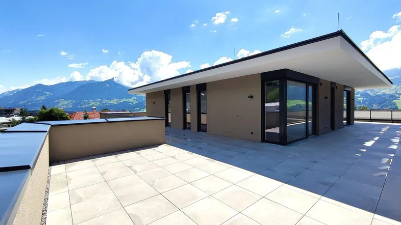 Große Dachterrasse mit modernen Fliesen und weitem Blick auf die umliegende Berglandschaft.