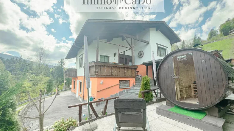 Traditionelles Haus in den Bergen mit Außensauna und Terrasse, umgeben von grüner Natur.