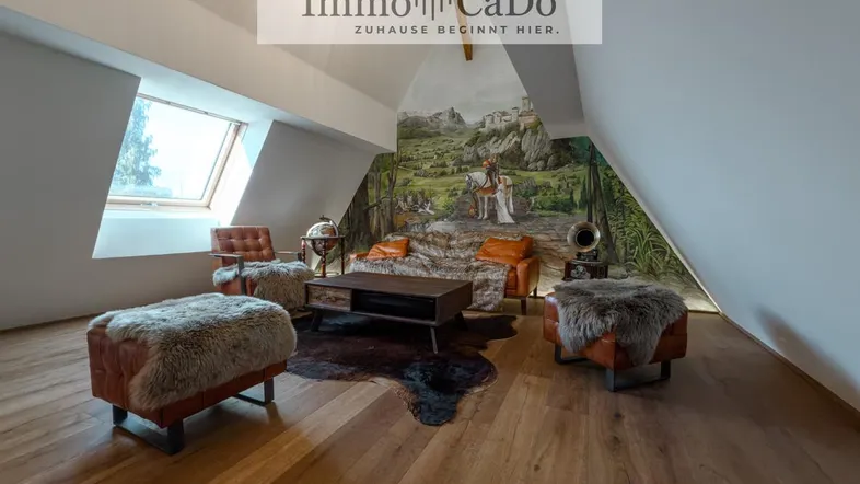 Gemütliches Dachgeschoss-Wohnzimmer mit Holzboden, Dachfenster und einer einzigartigen Wandmalerei.