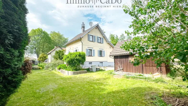 Großzügiger Gartenbereich mit Rasenfläche und Blick auf das charmante Einfamilienhaus.