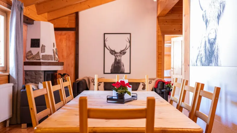 Gemütlicher Wohn-Essbereich im Chalet-Stil mit Holzbalken und Kamin.