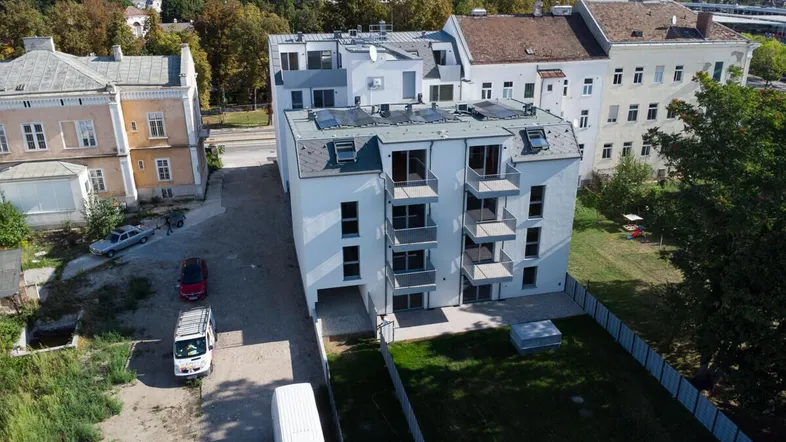 Luftaufnahme eines modernen Neubaus mit Balkonen und umliegenden Gebäuden.