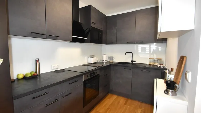 Moderne Küche mit dunklen Schränken, integrierten Geräten und Holzboden.