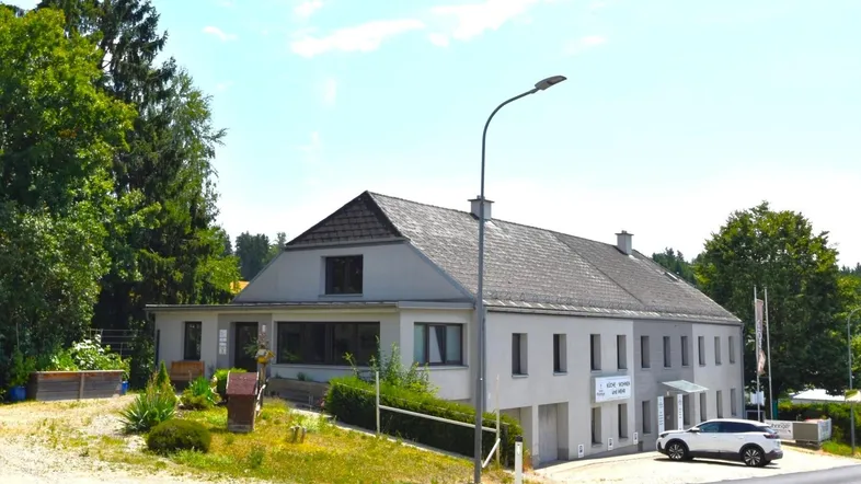 Gebäudeansicht mit moderner Architektur, großen Fenstern und gepflegter Umgebung.