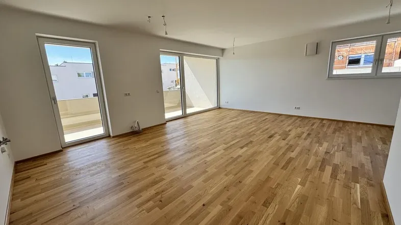 Helles Wohnzimmer mit neuem Parkettboden und Zugang zu einer großen Terrasse.