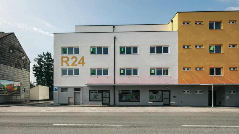 Modernes Geschäftsgebäude mit weißer und gelber Fassade, direkt an einer Straße gelegen.