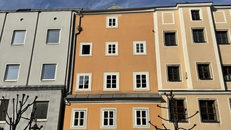 Historische Fassade eines Stadthauses mit mehreren Fenstern und Geschäften im Erdgeschoss.