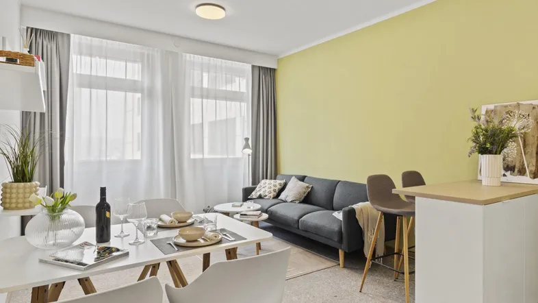 Helles Wohn- und Esszimmer mit moderner Einrichtung, Sofa, Esstisch und integrierter Küchenzeile.