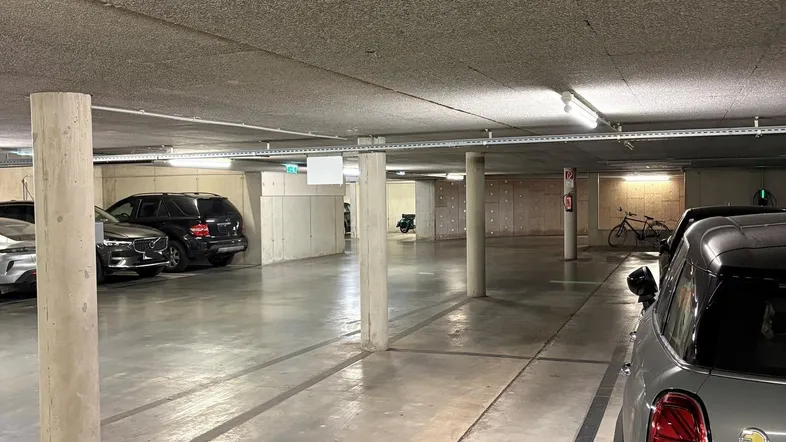 Geräumige Tiefgarage mit Betonboden und Säulen, bietet ausreichend Parkplätze für Fahrzeuge.