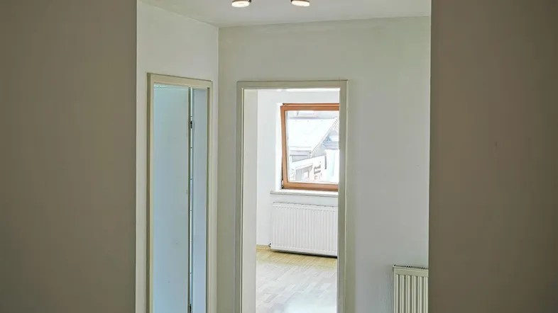 Heller Flur mit Holzfußboden und Zugang zu weiteren Räumen, gut beleuchtet durch Tageslicht.