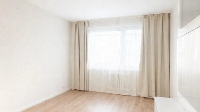 Helles, leeres Zimmer mit Laminatboden und großen Fenstern, bereit zur individuellen Gestaltung.