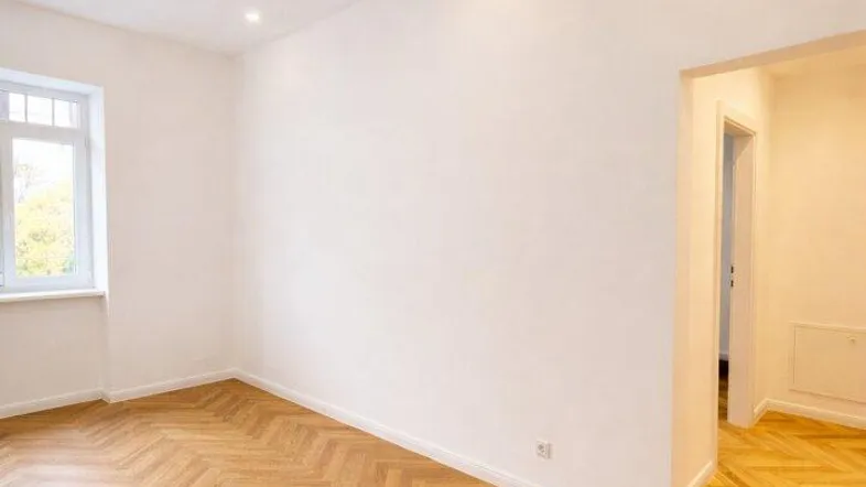 Helles Zimmer mit Fischgrätparkettboden und Einbaustrahlern, ideal als Wohnzimmer nutzbar.