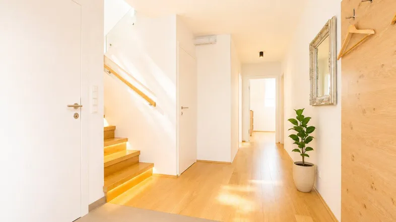 Heller Flur mit Holztreppe und Garderobe, der zu den oberen Etagen führt.