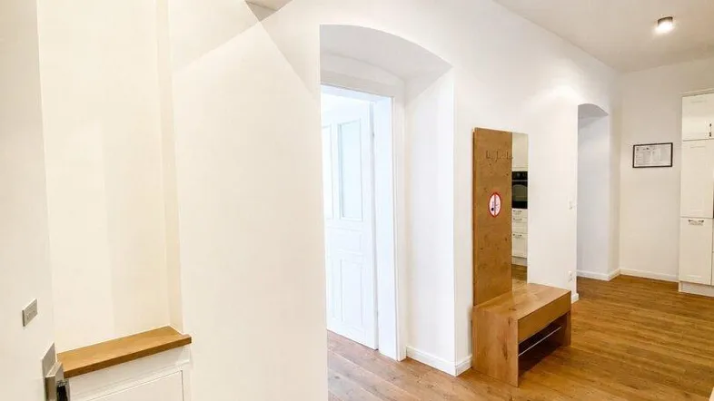 Helle Diele mit Holzfußboden und Zugang zu weiteren Räumen, modern und einladend gestaltet.