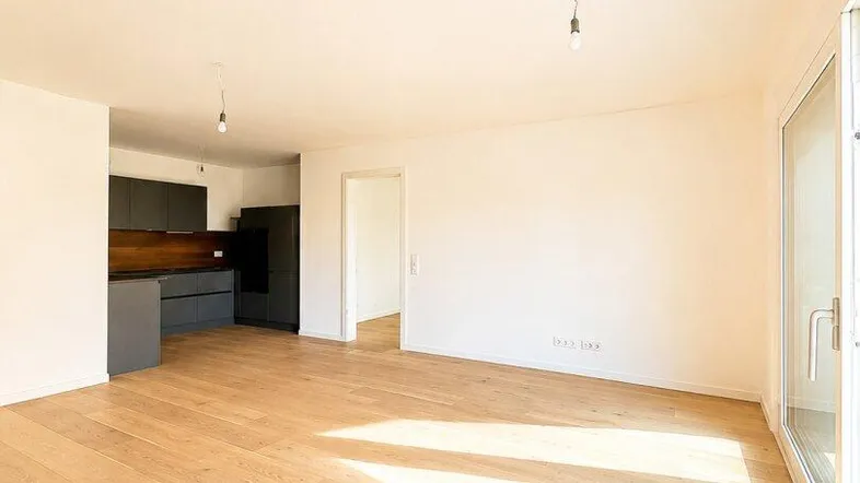 Heller, offener Wohnbereich mit Holzboden und integrierter Küche, lichtdurchflutet durch große Fenster.
