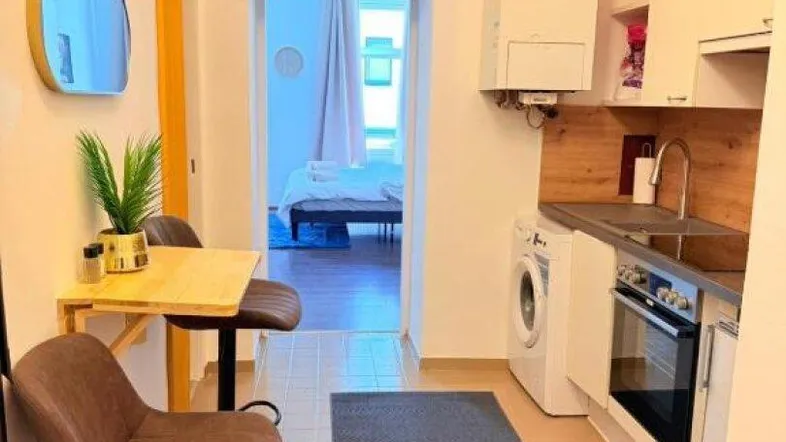 Kleine Küche mit integrierter Waschmaschine und Blick in das angrenzende Schlafzimmer.
