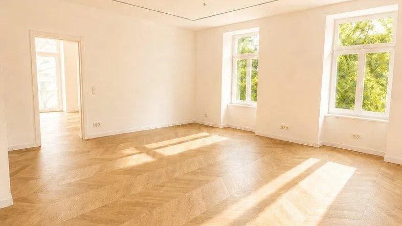 Helles, leeres Wohnzimmer mit Fischgrätparkett und großen Fenstern, bereit zur individuellen Gestaltung.