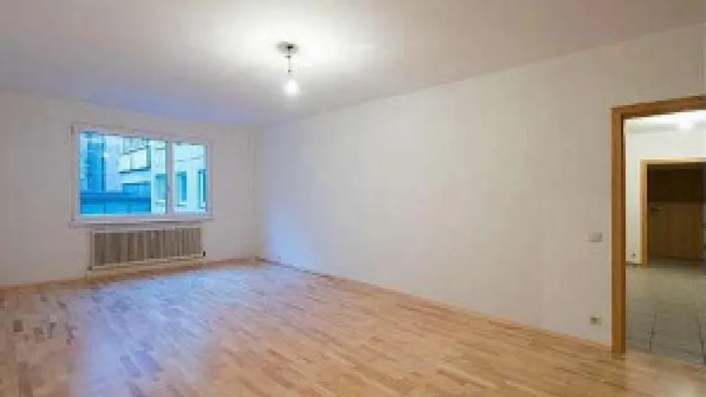 Helles, leeres Zimmer mit Holzboden und weiß gestrichenen Wänden, bereit zur individuellen Gestaltung.