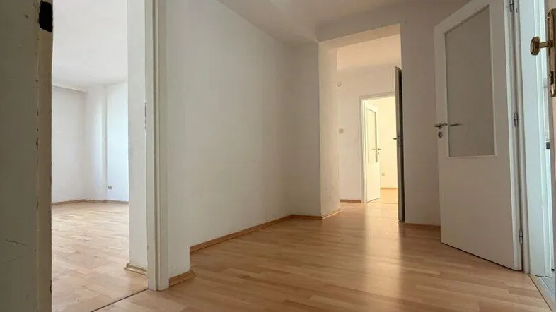 Heller Flur mit Laminatboden und Zugang zu mehreren Zimmern der Wohnung.