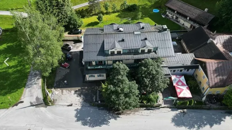 Luftaufnahme eines Gebäudekomplexes mit umliegender grüner Landschaft und Parkplätzen in ländlicher Umgebung.